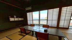 Een kamer met tatami matten, een lage tafel, stoelen en uitzicht door shoji schermen.