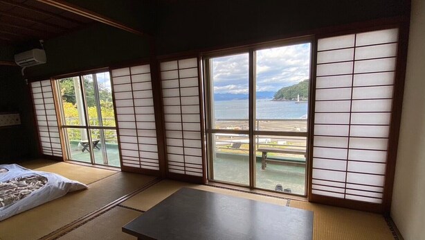 Een kamer met tatami matten en uitzicht op zee, met een tafel.