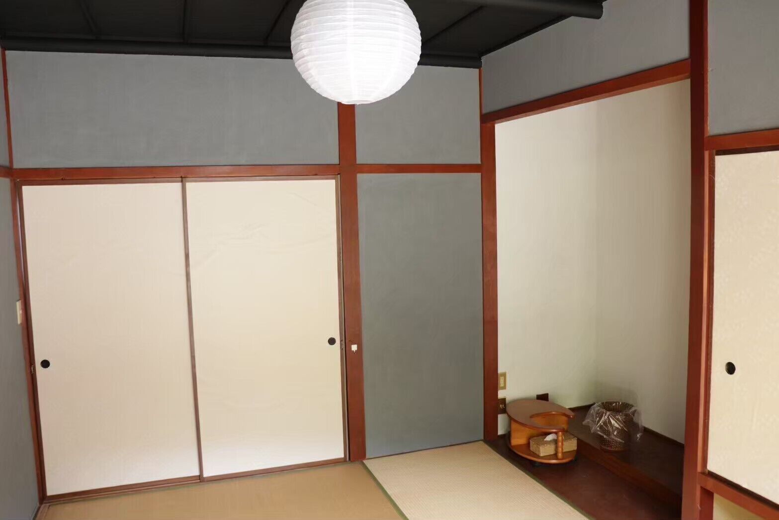 A traditional Japanese room with tatami flooring, sliding doors, and a hanging paper lantern.
