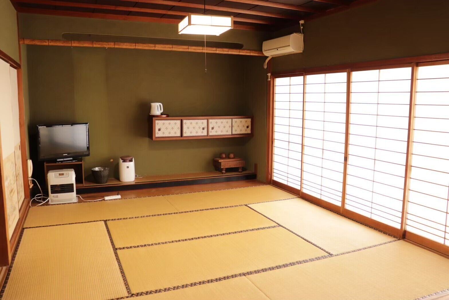 Una habitación con tatami, televisión, aire acondicionado y puertas correderas.