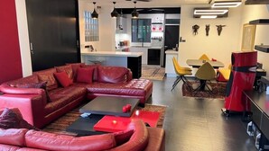 Una sala de estar moderna con un sofá de cuero rojo, una mesa de centro negra y una zona de comedor con sillas amarillas.