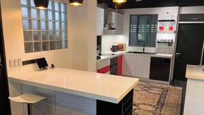Una cocina moderna con una isla grande, iluminación colgante y un tapete estampado.