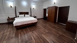 Une chambre à coucher avec un lit, un plancher en bois, un ventilateur de plafond et une armoire.