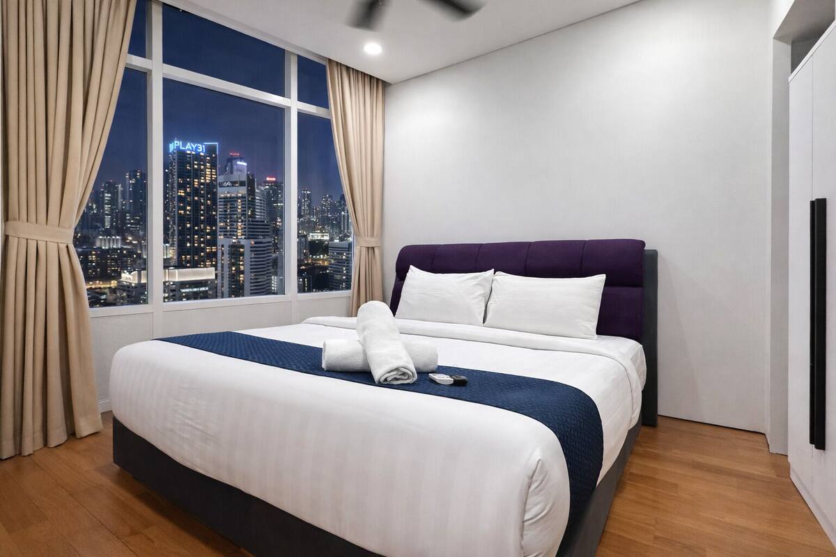A hotel room with a bed, a city view, and a modern design.