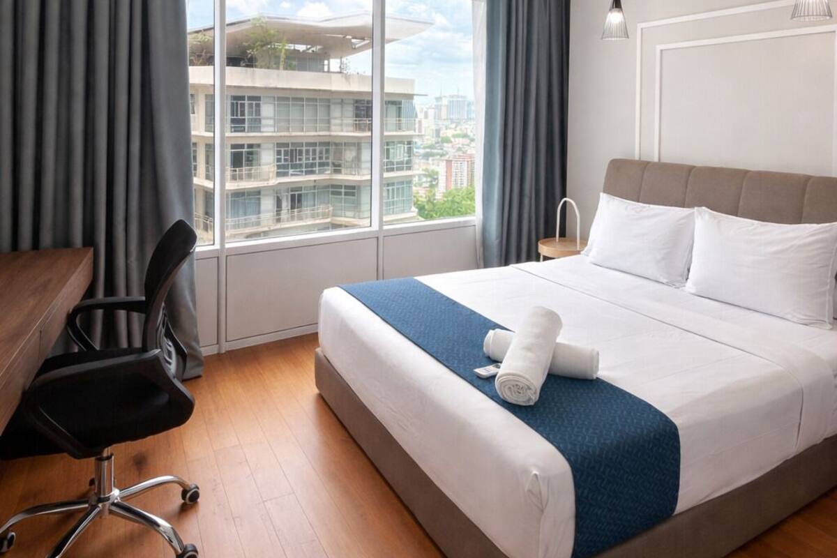 A modern hotel room with a large bed, a desk, and a chair.