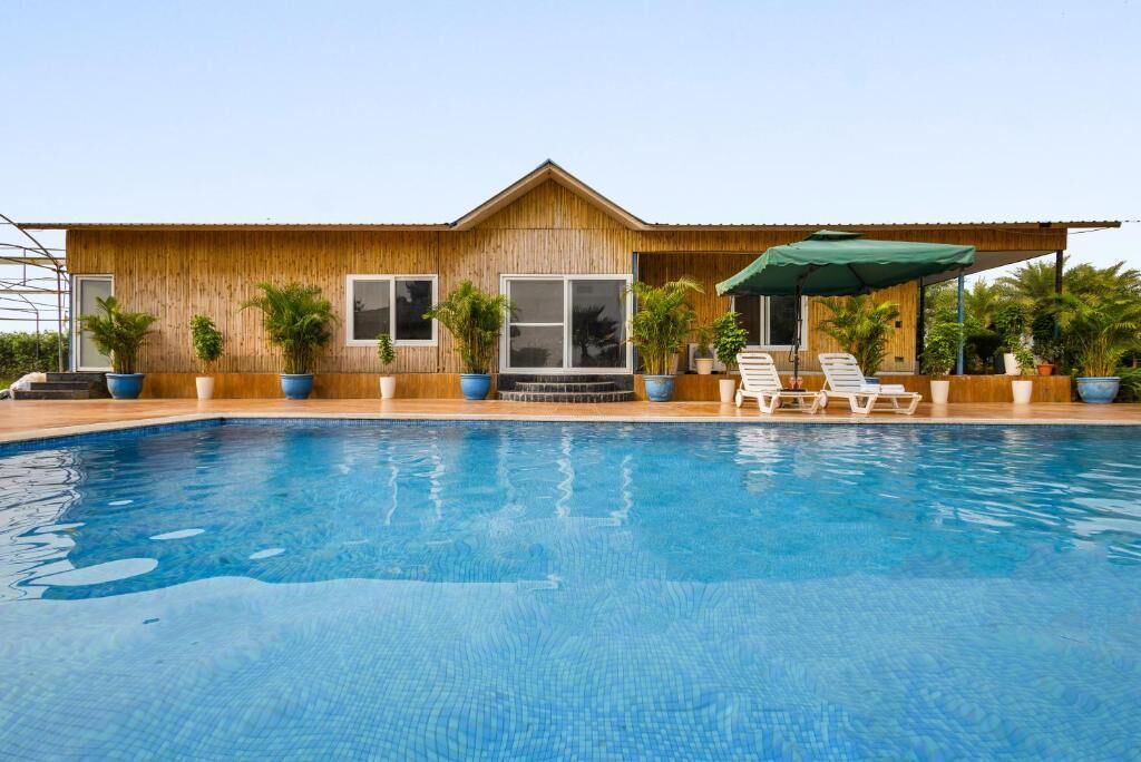 A poolside area with a wooden building, a pool, and lounge chairs.