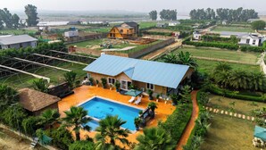 Une grande maison avec une piscine, entourée d’une végétation luxuriante et offrant une vue sur une rivière.