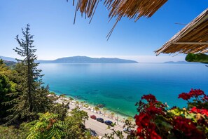 A coastal view with a clear sky, a road leading to a beach, and a mountain range in the distance. - Beach Front Terace (Qendër Vlorë)