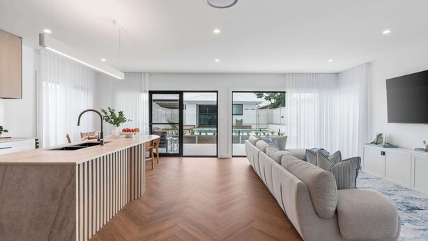 Eine moderne Küche mit Kochinsel, ein Essbereich mit Blick auf den Pool und ein Wohnzimmer mit Sofa und Fernseher.