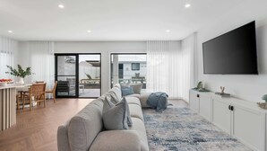 Ein modernes Wohnzimmer mit einer Couch, einem Flachbildfernseher und einem Essbereich mit Stühlen und einem Tisch.