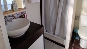 Un bany amb un benedormer blanc, un mirall, una cortina de bany i un vàter.