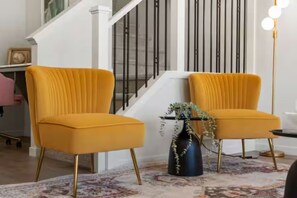 A staircase with black railings, two yellow chairs with gold legs, and a vase with plants on a patterned rug. - Charming 3-bedroom house in beautiful Calgary with AC (Calgary)