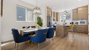 Una cocina moderna con armarios de madera, una isla central y un comedor con sillas azules.