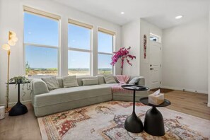 Ein Wohnzimmer mit großem Fenster, einer Couch, einem Couchtisch und einer Zimmerpflanze.