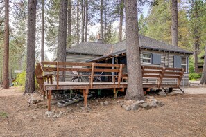 Uma cabana com deck de madeira e área de estar coberta ao ar livre.