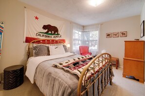 Ein Schlafzimmer mit einem Bett, einer Flagge, einem Sessel, einem Holzschrank und einem Fenster.