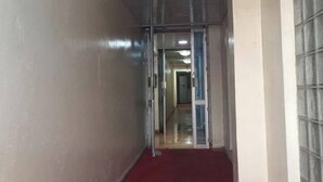 A corridor with a red carpet, metal ceiling, and glass doors leading to another room. - Jundan Palace Hotel Mombasa (Mombasa)