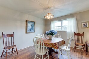 A dining room with a round table, six chairs, a chandelier, and a window with curtains. - Rural Group Getaway w/ Creek Access in Berryville! (Berryville)