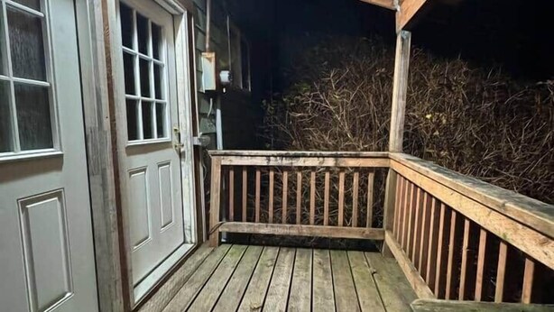 En träaltan med ett räcke, en dörr och en bänk.