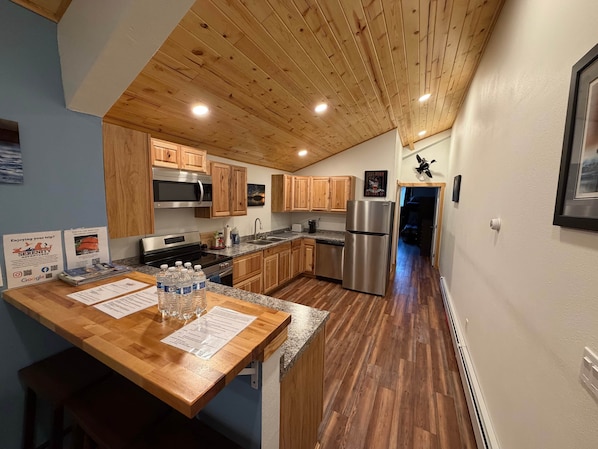 Une cuisine moderne avec des armoires en bois, des appareils électroménagers en acier inoxydable et un plafond en bois.