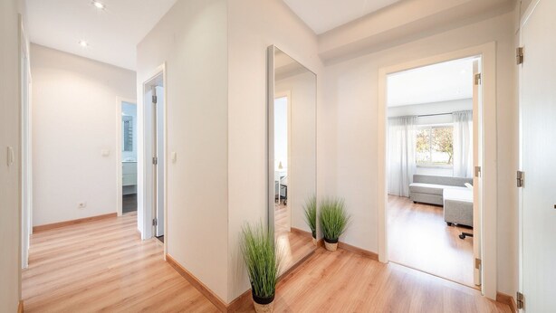 A modern interior with a wooden floor, a hallway leading to a room with a bed and a window. - GuestReady - Retreat in Almada (Almada)