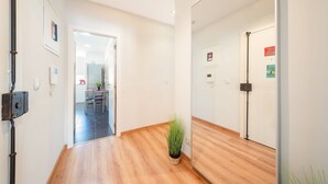 A hallway with wooden flooring, a potted plant, and a door with a security lock. - GuestReady - Retreat in Almada (Almada)
