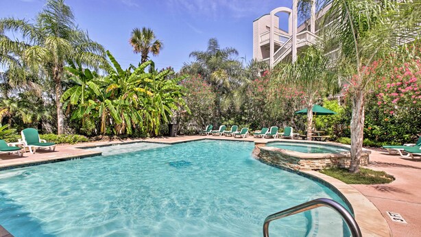 Une piscine avec des chaises longues et des palmiers.