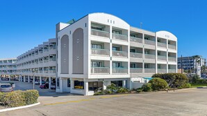 Un hôtel à plusieurs étages, doté d’une façade incurvée, de balcons et d’un parking.