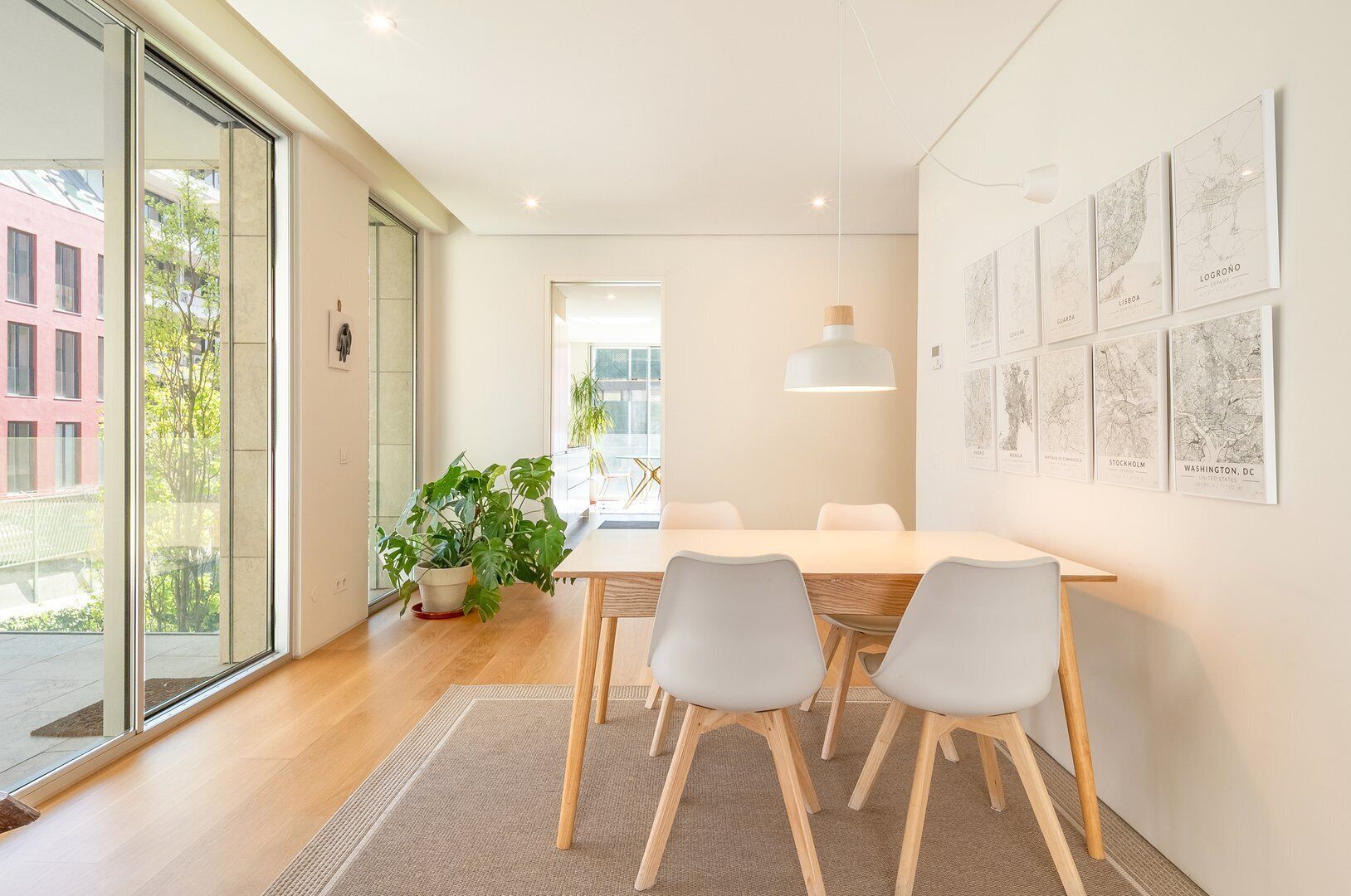 Un espace de salle à manger moderne comprenant une table, des chaises, un luminaire suspendu et une décoration murale représentant un paysage urbain.