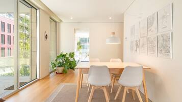 Un espace de salle à manger moderne comprenant une table, des chaises, un luminaire suspendu et une décoration murale représentant un paysage urbain.