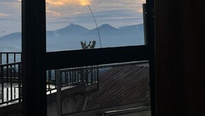 A room with a large window overlooking mountains and a clear sky.