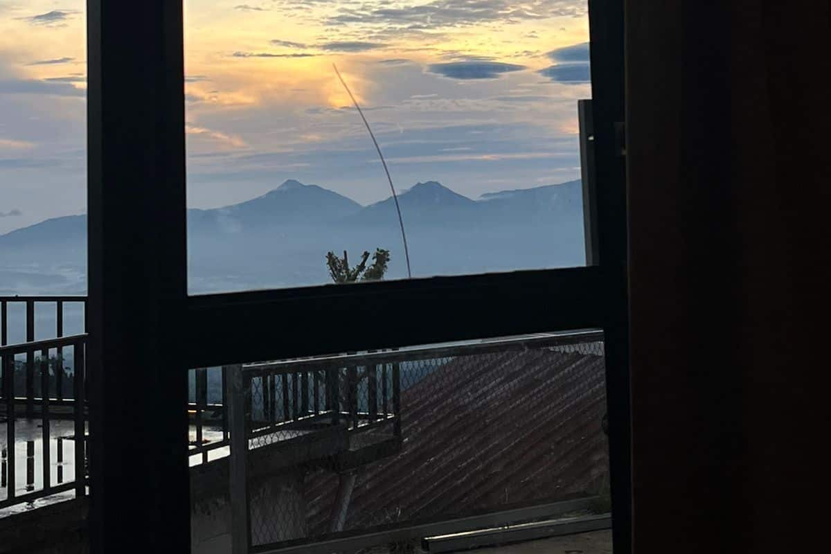 A room with a large window overlooking mountains and a clear sky.