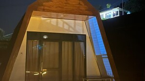 A triangular-shaped building with a glass door and a metal railing in front.