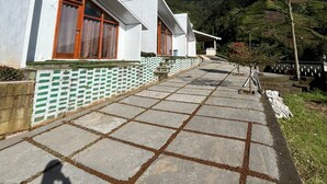 A row of white buildings with wooden doors and windows, a stone-paved pathway, and a mountainous backdrop.