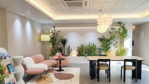 A modern interior with a sofa, a dining table, chairs, and a variety of plants. - 4rest Stay Jongno (Seoul)