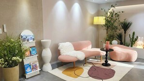 A modern living room with a pink sofa, a white fluffy throw, a round table, a lamp, and a potted plant. - 4rest Stay Jongno (Seoul)