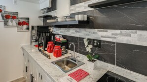 Cucina con piano di lavoro in marmo, zoccolo nero e bianco e diversi utensili.
