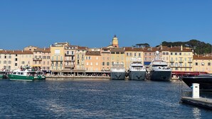 A marina with boats docked, a clear blue sky, and buildings with a uniform architectural style.