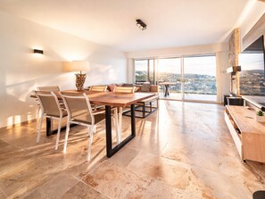 A spacious living area with a large dining table, comfortable seating, a fireplace, and a view of the city. - Beautiful villa with airco, pool and hottub (Les Issambres)