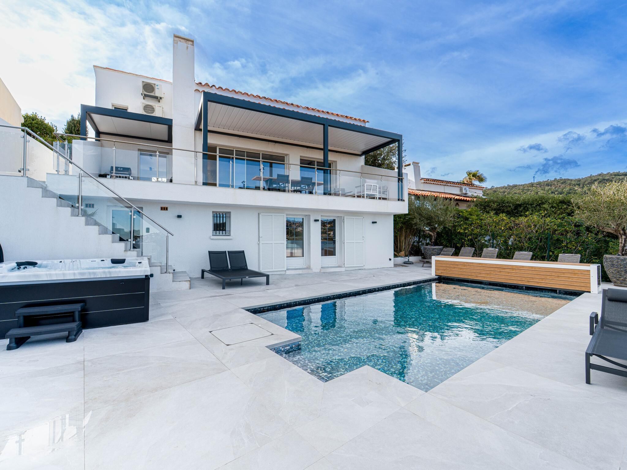 A modern two-story house with a swimming pool, outdoor seating, and a staircase leading to the upper level.