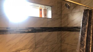 A bathroom with a shower, a mirror, and toiletries on the wall.