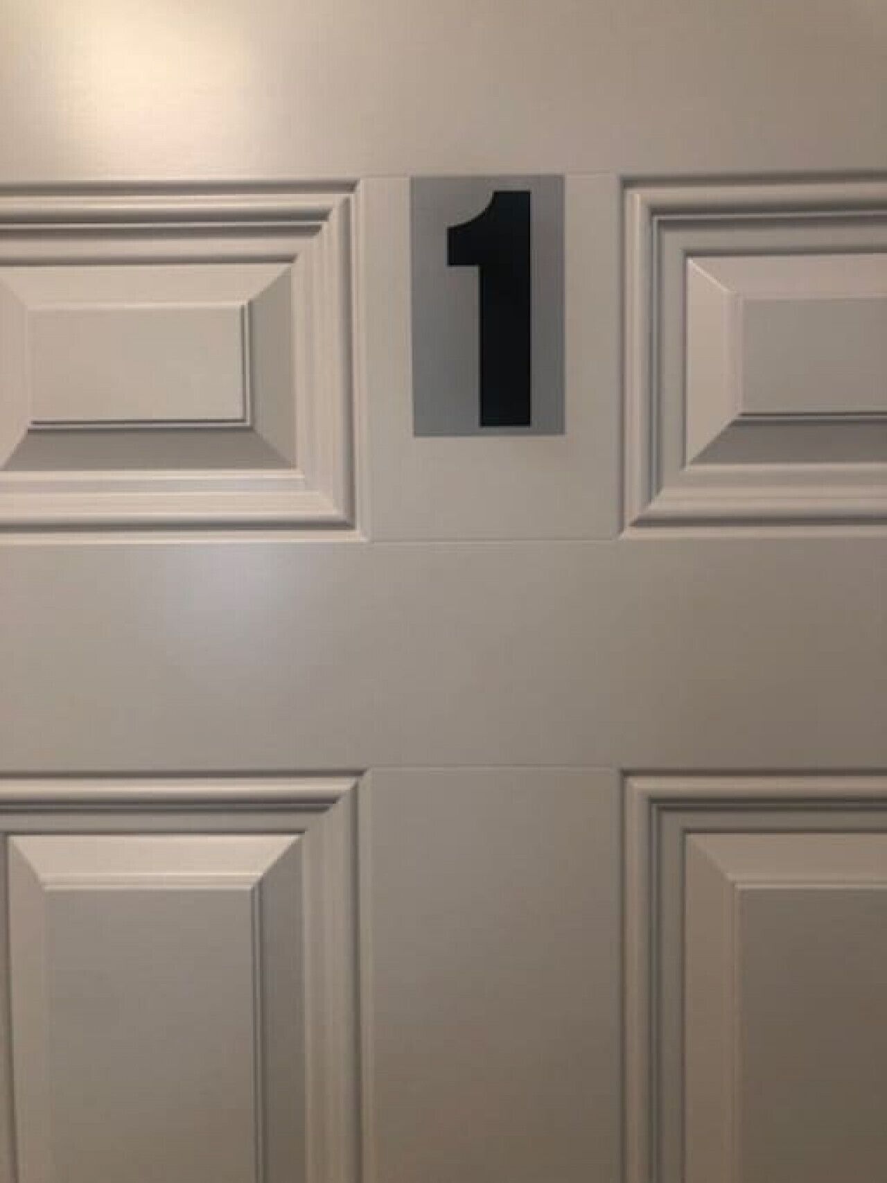 Une porte sur laquelle est apposé un panneau indiquant le numéro « 1 », ce qui correspond au numéro de la pièce.