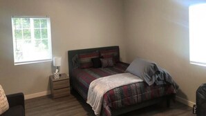 A bedroom with a bed, nightstand, and window.