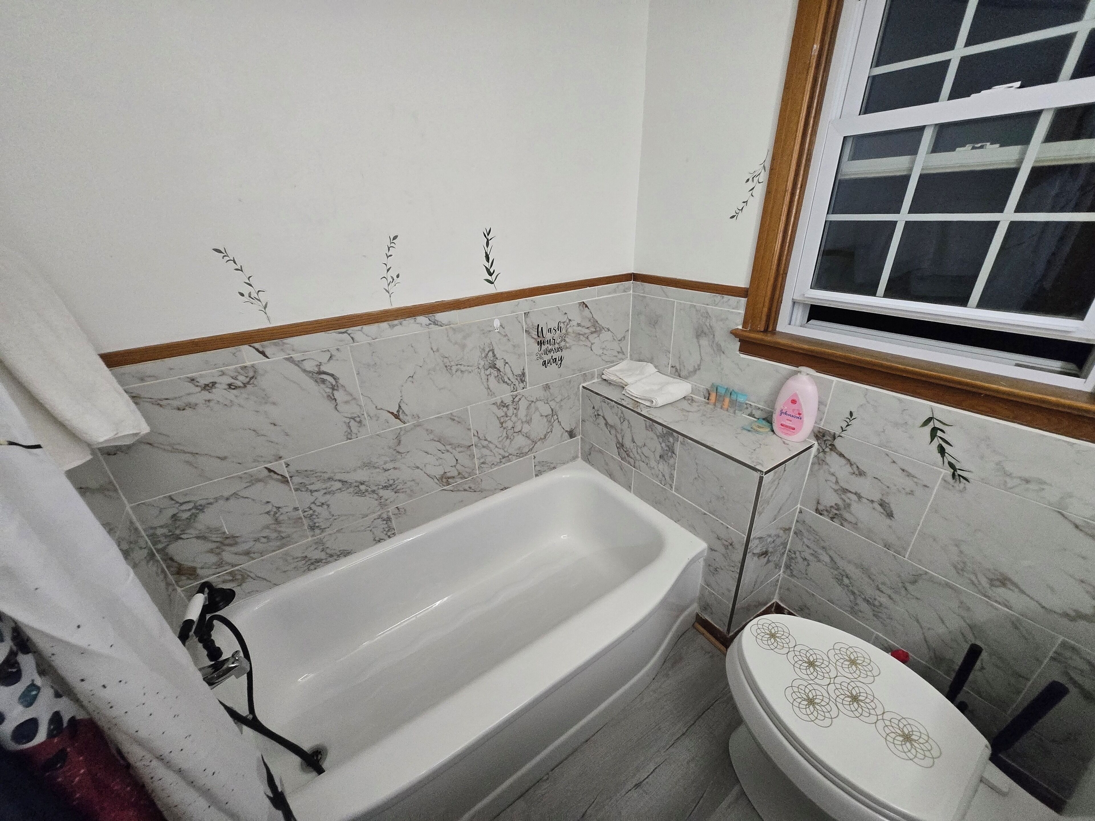 A bathroom with a bathtub, toilet, and a window.