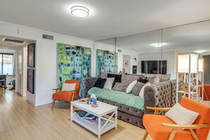 Ein modernes Wohnzimmer mit gepolstertem Sofa, Couchtisch und orangefarbenem Sessel.