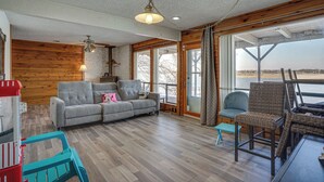 Ein geräumiges Wohnzimmer mit grauem Sofa, einem Korbstuhl und einem kleinen Tisch.