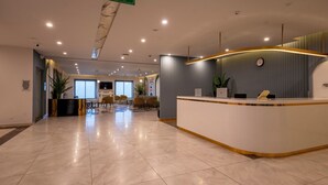 Ein Hotel-Empfangsbereich mit einer gebogenen Rezeption, einer Uhr und einem Notausgangsschild.