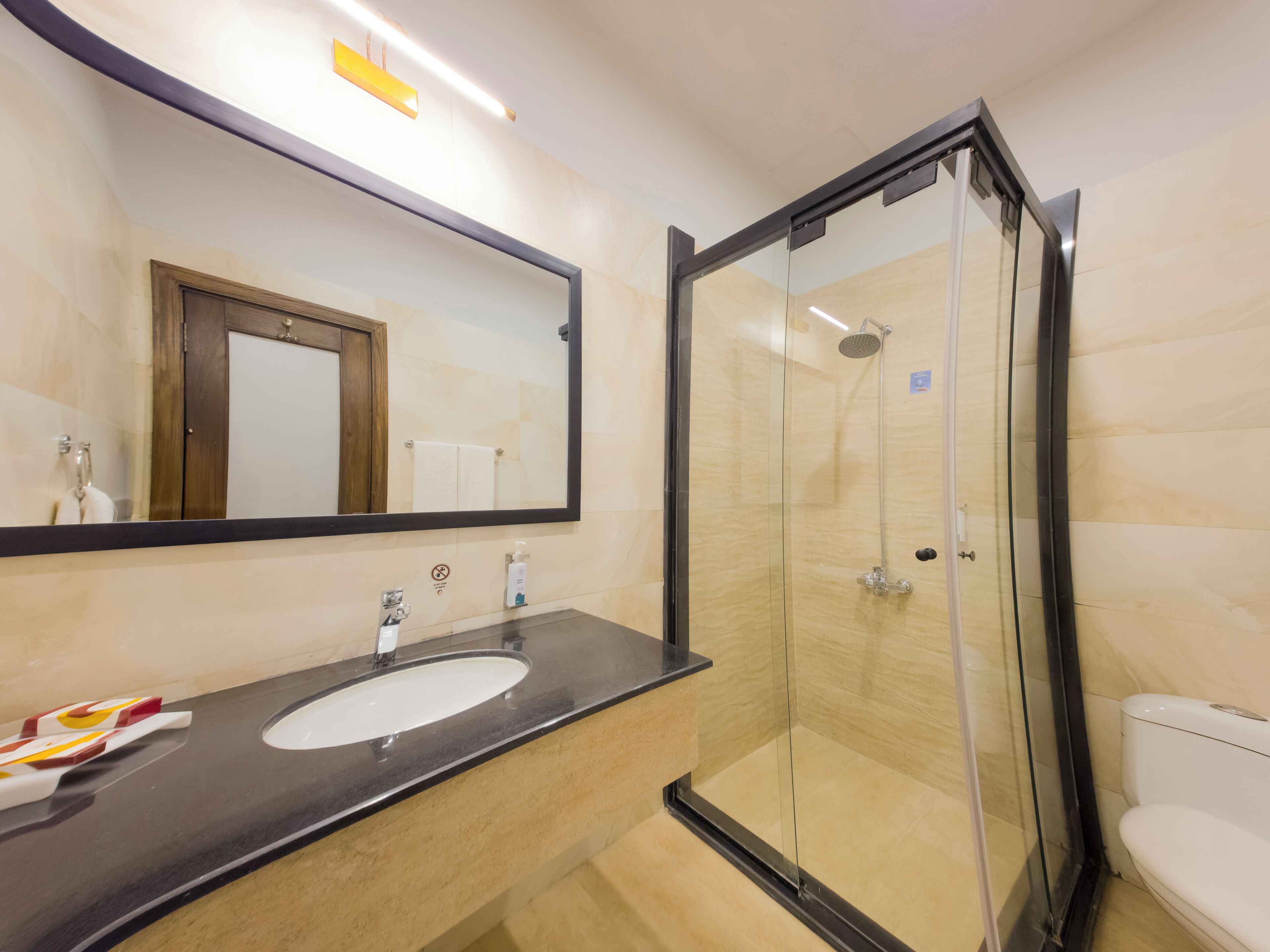 Un baño con ducha de vidrio, lavamanos y espejo.
