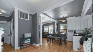 A spacious kitchen with wooden flooring, white cabinetry, and a dining area with a table and chairs. - Remodeled Historic Folsom Craftsman House - Pool - Walk to Sutter St (Folsom)