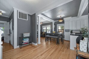 A spacious kitchen with wooden flooring, white cabinetry, and a dining area with a table and chairs. - Remodeled Historic Folsom Craftsman House - Pool - Walk to Sutter St (Folsom)